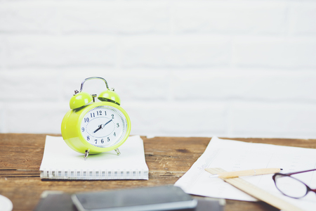 alarm clock with notebook on wooden table