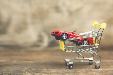 Car shopping, red luxury sports car in a shopping basketの写真素材