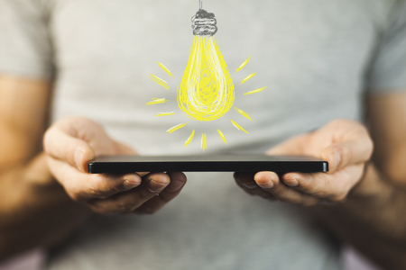 Hand holding smartphone with Light Bulb - Idea concept.の写真素材