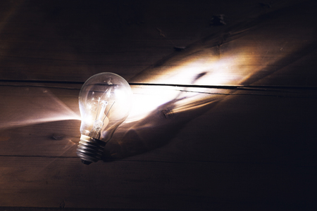 Glowing light bulb on wooden backgroundの写真素材