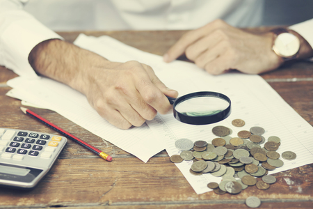 Businessman Calculating Bills In Front Of Stacked Coinsの写真素材