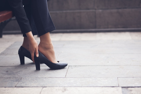 Business woman sit on the street chair and push her leg take a rest.の写真素材