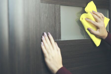 hand cleaning a door with a yellow cloth