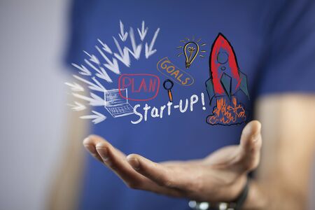 Businessman on blurred background holding hand drawn startup text and red rocketの写真素材