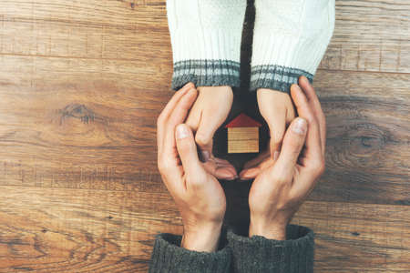 couple hand house model on wooden table