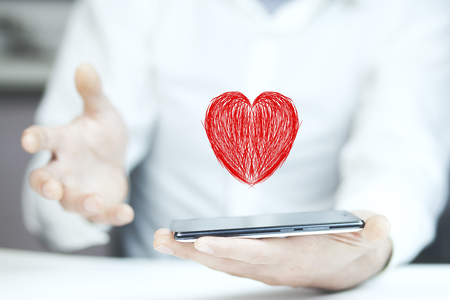 man holding smartphone with red heart on white backgroundの写真素材