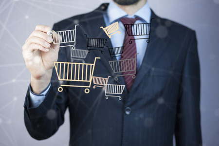 Business man hand pen  with shopping basketの写真素材