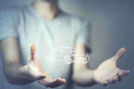 Man's hands holding virtual car on blurred backgroundの写真素材