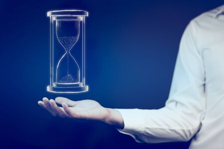 Man's hand holding hourglass sandの写真素材