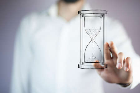 Man's hand holding hourglass sandの写真素材
