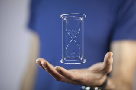 Man's hand holding hourglass sand 
