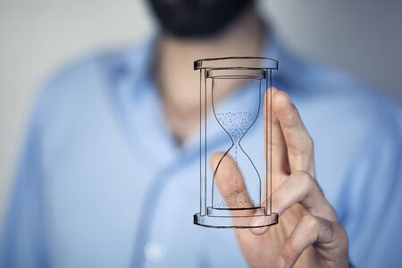 Man's hand holding hourglass sand 