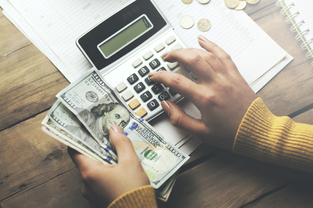 woman write and calculator with money on business documents backgroundの写真素材