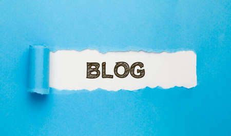 Blog text written on torn paper on blue background