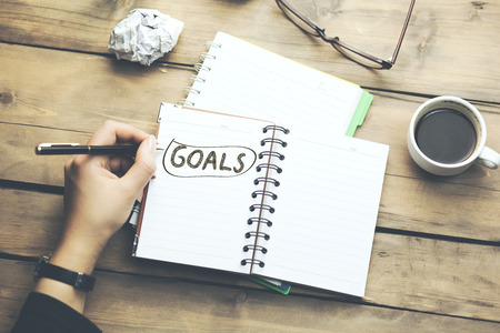  
woman written goals text on notepad with coffee on tableの写真素材