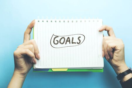 
 goals text on notepad on woman hand on blue backgroundの写真素材