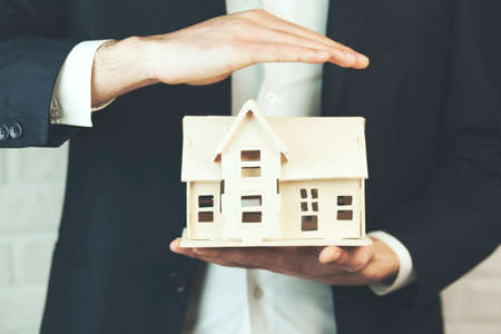 Businessman holding a toy house model in studioの写真素材
