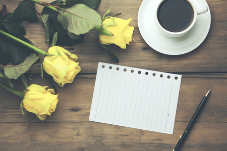 yellow roses with page and coffee on the wooden tableの写真素材