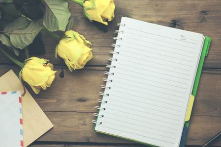 yellow roses with notepad on the wooden tableの写真素材