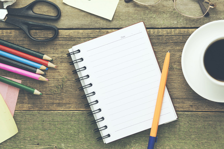notepad with cup of coffee and stationary on tableの写真素材