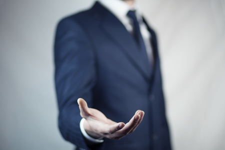 male is standing and shows outstretched hand with open palmの写真素材