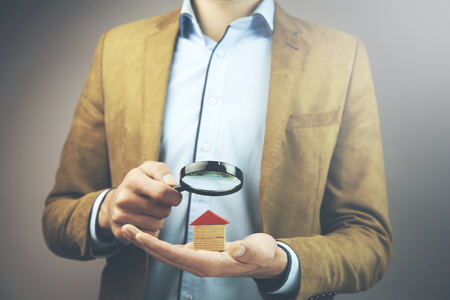 man hand holding house model with magnifierの写真素材