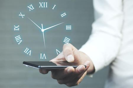 Businessman hand phone with  clock in the screenの写真素材