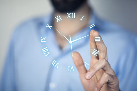 Businessman hand holding clock in the screenの写真素材