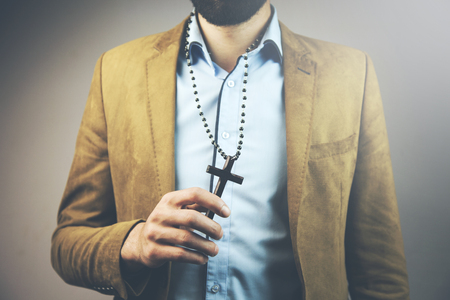 young businessman neck cross necklace in studioの写真素材