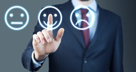 Businessman hand pointing the smiley face icon from screen as positive feedback conceptの写真素材