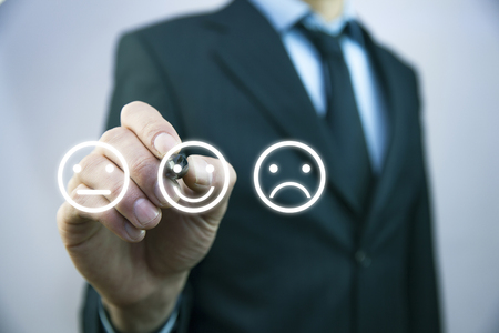 Businessman hand pointing the smiley face icon from screenの写真素材