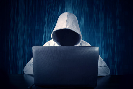 Hacker typing on a laptop with binary code in backgroundの写真素材
