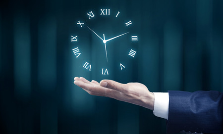 young businessman hand holding clock in screenの写真素材