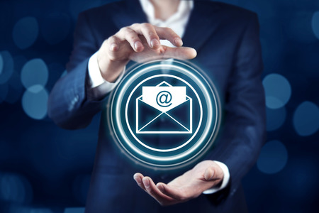 Businessman on blurred background touching  flying email icon with his fingerの写真素材
