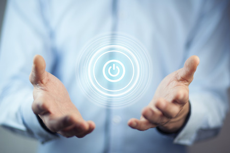 Businessman on blurred background holding render power button with his hand