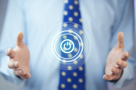 Businessman on blurred background holding render power button with his hand