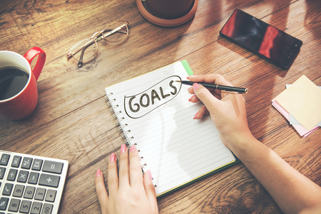 woman  writing goals text on   notepad and stationary on tableの写真素材