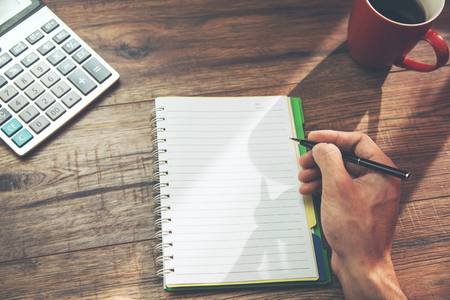 businessman hands writing in notepad  and calculator on tableの写真素材