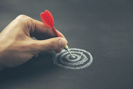 hand take a dart into the center of sketching dartboard