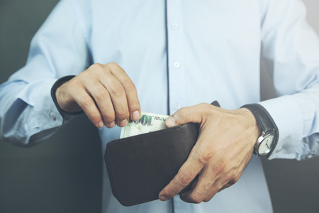 businessman hand holding a wallet with money in dark backgroundの写真素材