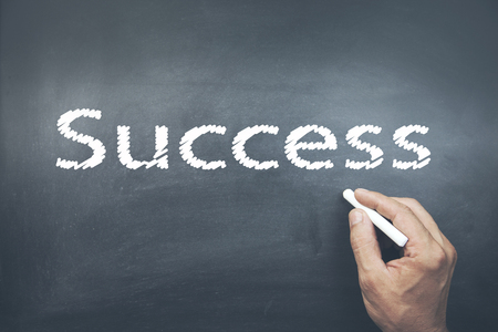 A person drawing and pointing at a  Success Chalk on boardの写真素材