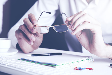business man hand holding glasses with document on tableの写真素材
