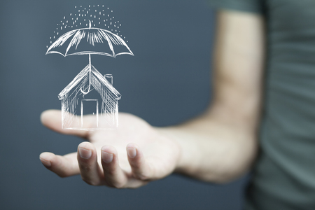 Businessman holding a drawing of umbrella over houseの写真素材