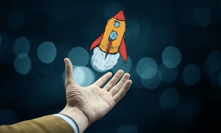 Businessman hand with a red rocket on grey backgroundの写真素材