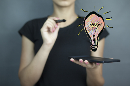 woman hand tablet with light bulb in screenの写真素材
