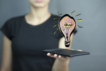 woman hand tablet with light bulb in screenの写真素材