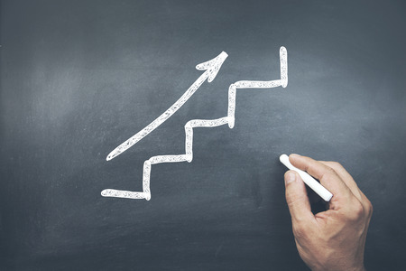 young business man drawing stairs on chelkboardの写真素材