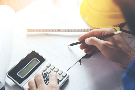 young male architect working on blueprints spread out on a tableの写真素材