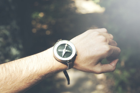 Mans hand holding a compass in nature