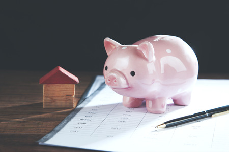 Piggy bank and model house on cash suggesting savings for houseの写真素材